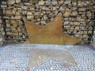 Zerbrochener Davidstern als Symbol für das zerstörte jüdische Leben Ein zerbrochener Davidstern auf Kies; Symbol für zerstörtes jüdisches Leben vor einer Steinwand.