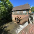 Molenrad van de Meyenburg watermolen met beek en molengebouw.