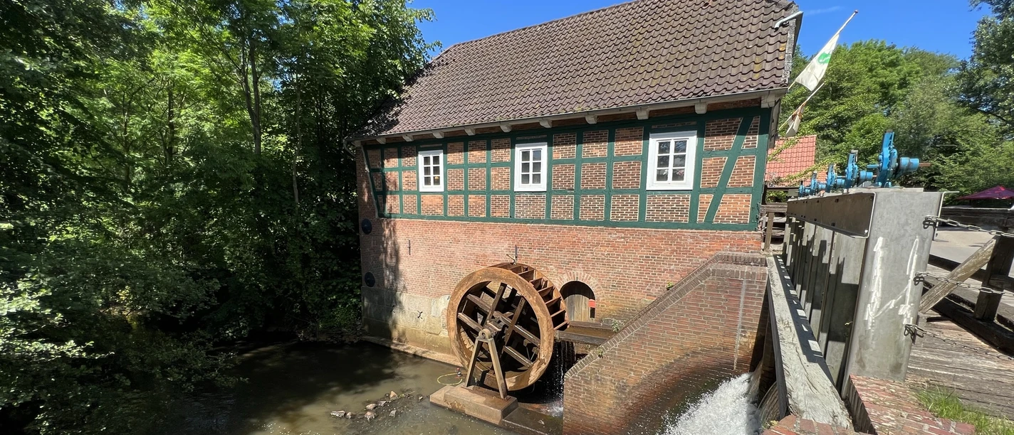 Wassermühle Meyenburg Mill wheel of the Meyenburg watermill with stream and mill building.