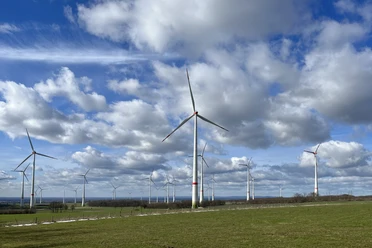 Windräder auf der Paderborner Hochfläche Windräder drehen sich auf der Paderborner Hochfläche unter einem bewölkten Himmel in einer grünen Landschaft.
