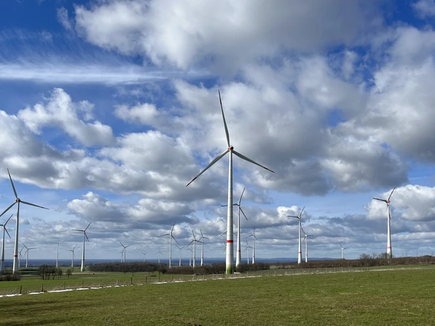 Windräder auf der Paderborner Hochfläche Windräder drehen sich auf der Paderborner Hochfläche unter einem bewölkten Himmel in einer grünen Landschaft.