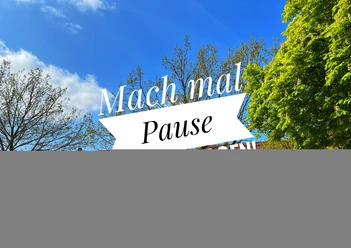 Blauer Himmel mit Bäumen und dem Schriftzug "Mach mal Pause" auf einem Banner in Petershagen.