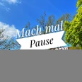 Blauer Himmel mit Bäumen und dem Schriftzug "Mach mal Pause" auf einem Banner in Petershagen.