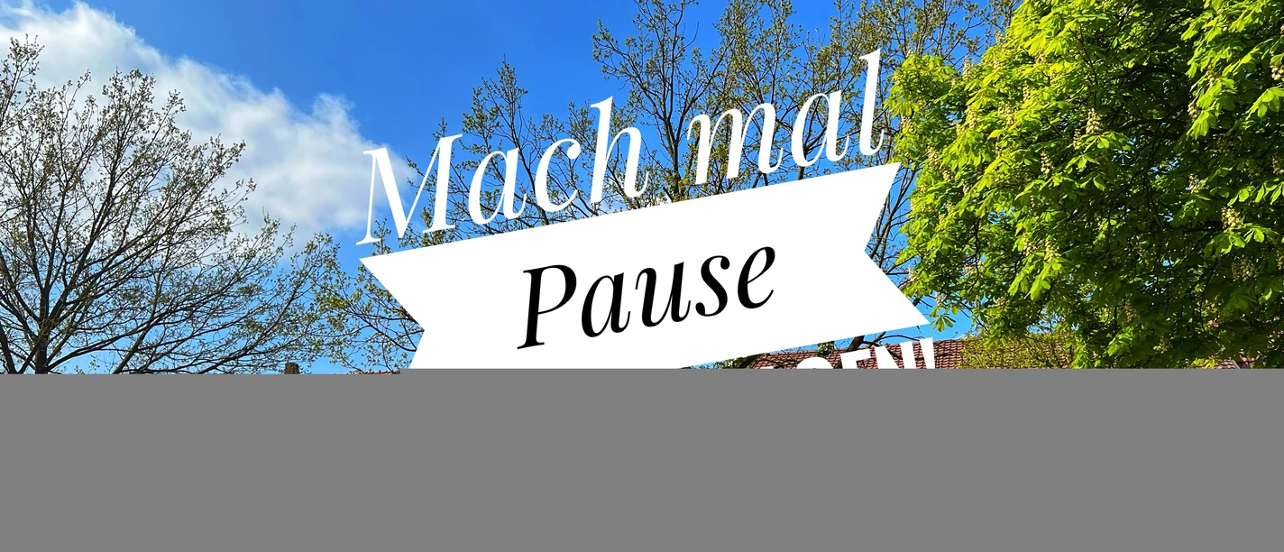 Mach mal Pause in Petershagen.jpg Blauer Himmel mit Bäumen und dem Schriftzug "Mach mal Pause" auf einem Banner in Petershagen.