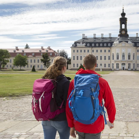 Pohled zezadu na dvojici při pohledu na zámek Hubertusburg ve Wermsdorfu, modrá obloha, mraky