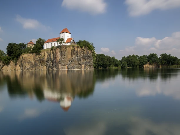 Mountain church on a rocky outcrop in Beucha, lake, blue sky, clouds, trees, nature