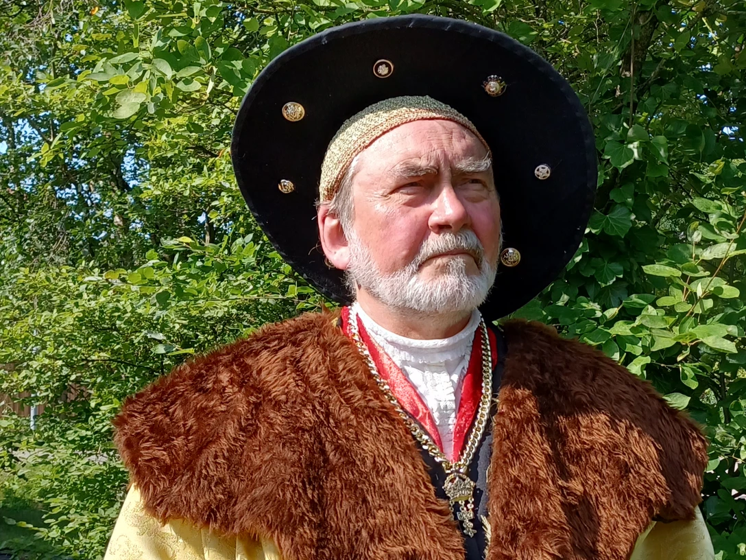 Edzard I. "der große" Cirksena Mann in historischer Kleidung mit Pelzkragen und großem Hut vor grünem Hintergrund im Freien.