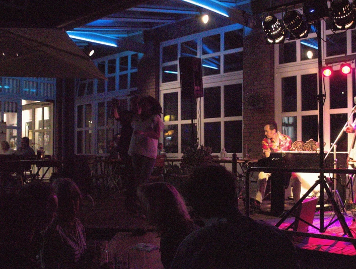 Druckerei Outdoor Musiker in stimmungsvoller Beleuchtung treten vor Publikum in einem städtischen Innenhof auf.