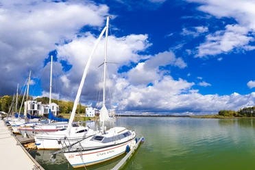 Boote liegen in der Lagune in Kahnsdorf an, Wasser, blauer Himmel, Wolken, Bäume, Häuser, Steg