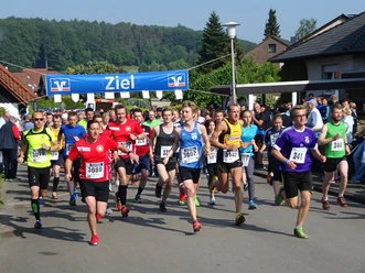 Volkslauf Rund um den Aussichtsturm.jpg Eine Gruppe von Läufern startet voller Energie bei einem Volkslauf unter einem "Ziel"-Banner.