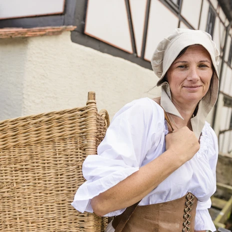 Woman in traditional costume with wicker basket at the inn Museum Wassermühle in Grimma in the Leipzig region