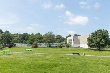 Scharoun Theater Wolfsburg Modernes Theatergebäude mit heller Fassade, großen Fenstern und umgebender grüner Parklandschaft.