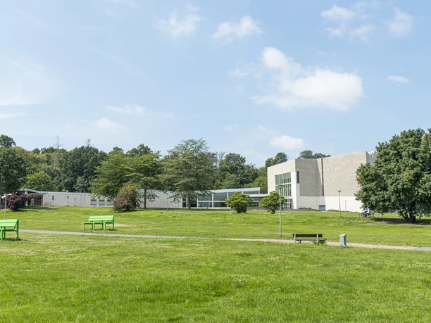 Scharoun Theater Wolfsburg Modernes Theatergebäude mit heller Fassade, großen Fenstern und umgebender grüner Parklandschaft.