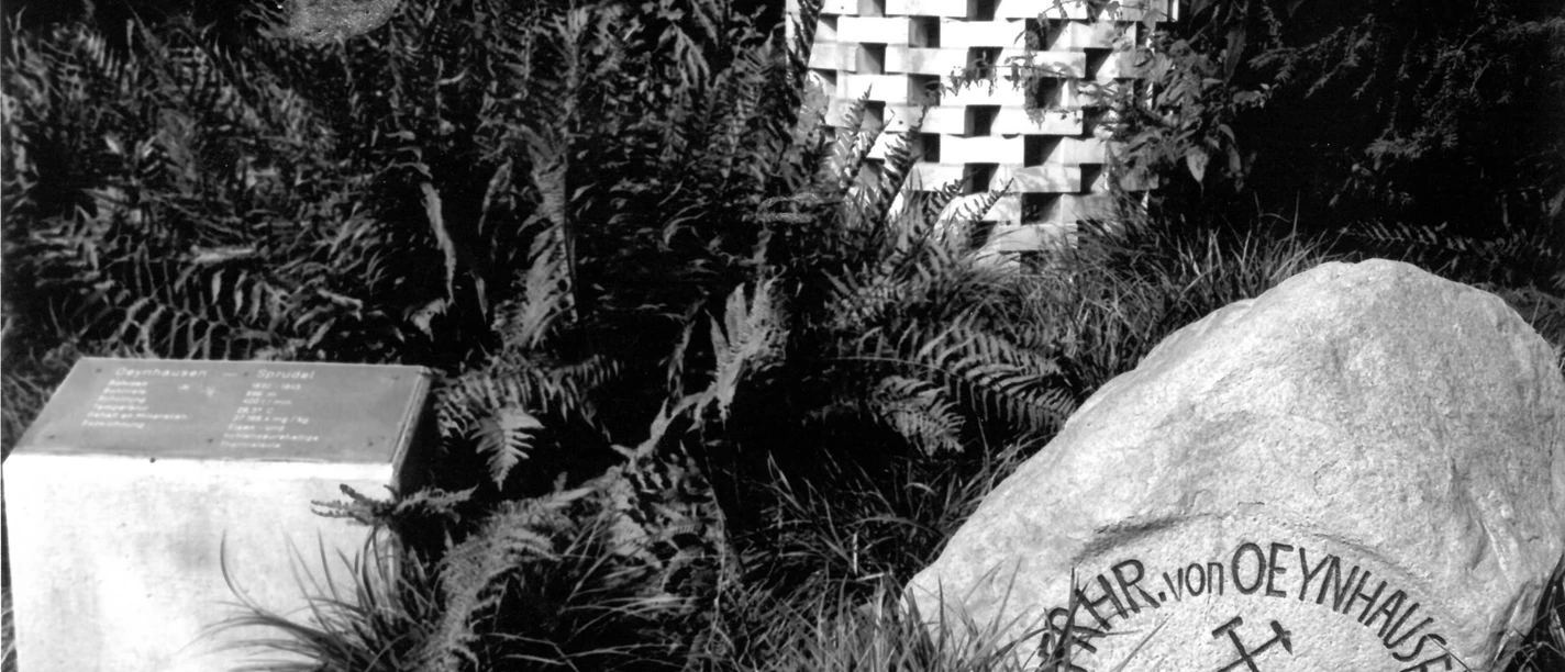 Oeynhausen-Sprudel, Rotunde um 1995 Stein mit Inschrift "Oeynhausen-Sprudel" und Gedenkstein in einer von Farnen umgebenen Parkanlage.