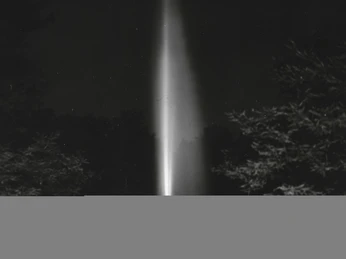 Jordansprudel bei Nacht, R. Langer, StABO.jpg Leuchtender Wasserstrahl des Jordansprudels in Bad Oeynhausen bei Nacht, umgeben von Bäumen.