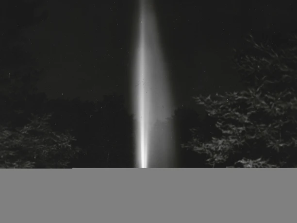 Jordansprudel bei Nacht, R. Langer, StABO.jpg Leuchtender Wasserstrahl des Jordansprudels in Bad Oeynhausen bei Nacht, umgeben von Bäumen.