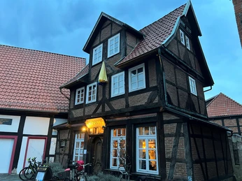 Weinhaus Nienburg Weinhaus in Fachwerkstil aus Holz und Backstein; abendlich beleuchtet, Fahrräder sind davor abgestellt.