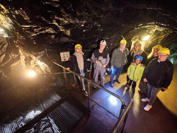 Am Emma-Schacht Gruppe von Menschen mit Helmen steht in einem beleuchteten, unterirdischen Steinbergwerk.
