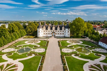 Luftaufnahme des Schlosses Neuhaus in Paderborn, umgeben von symmetrischen Gärten und Grünflächen.