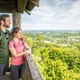 Borgholzhausen-Luisenturm-Teutoburger-Wald-Tourismus-D-Ketz-064.jpg Ein Paar steht auf einem Aussichtsturm, genießt weite Ausblicke über grüne Wälder und Landschaften.
