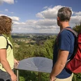 Steinhagen-Schwedenschanze-Teutoburger-Wald-Tourismus-F-Grawe (97).JPG Zwei Wanderer mit Rucksäcken betrachten von einer Aussichtsplattform aus die weite Landschaft des Teutoburger Waldes.
