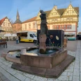 IMG_8829.jpg Marktplatz mit Brunnen, umgeben von historischen Fachwerkhäusern und Marktständen bei sonnigem Wetter.