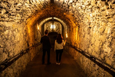 Bielefeld-Sparrenburg-Teutoburger-Wald-Tourismus-D-Ketz-024-CC-BY-SA.jpg <p>Ein Paar mit Fackeln erkundet einen historischen, beleuchteten Steintunnel. Mystische Atmosphäre.</p>