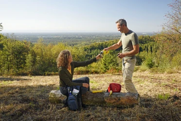 Oerlinghausen-Ausblick-ins-Lipperland-Teutoburger-Wald-Tourismus-F-Grawe (64).JPG Zwei Personen auf einer Lichtung im Teutoburger Wald, tauschen Getränke mit bewaldetem Lipperland im Hintergrund.