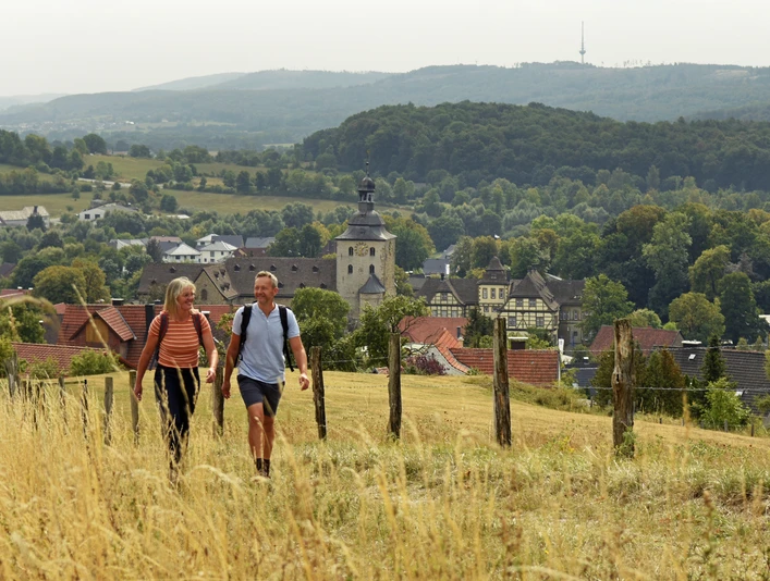 Bad-Driburg-Neuenheerse-Teutoburger-Wald-Tourismus-F-Grawe (14).JPG Zwei Wanderer auf einem Feldweg mit Blick auf Neuenheerse und die waldige Hügellandschaft.