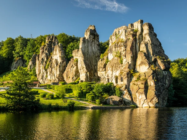 Externsteine Horn-Bad Meinberg Felsenformation Externsteine erhebt sich imposant aus grüner Landschaft, umgeben von ruhigem Wasser.