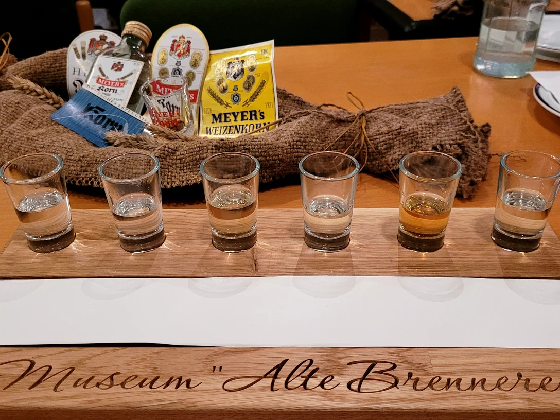 Sechs Schnapsgläser auf einem Holzkastl mit der Aufschrift "Museum Alte Brennerei", Tasting-Set.