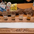 Sechs Schnapsgläser auf einem Holzkastl mit der Aufschrift "Museum Alte Brennerei", Tasting-Set.