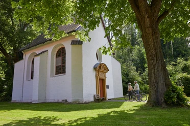 Borchen-Kluskapelle-Teutoburger-Wald-Tourismus-T-Evers-110.jpg Zwei Radfahrer betrachten eine kleine, weiße Kapelle im Grünen, umgeben von Bäumen.