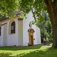 Borchen-Kluskapelle-Teutoburger-Wald-Tourismus-T-Evers-110.jpg Zwei Radfahrer betrachten eine kleine, weiße Kapelle im Grünen, umgeben von Bäumen.