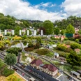 Eisenbahnwelten im Kurort_Rathen Miniaturlandschaft mit Modellbahn, umgeben von bunten Gebäuden und grünen Bäumen, unter einem bewölkten Himmel.Miniature landscape with model railroad, surrounded by colorful buildings and green trees, under a cloudy sky.Miniaturní krajina s modelem železnice, obklopená barevnými budovami a zelenými stromy, pod zataženou oblohou.Miniaturowy krajobraz z modelem kolejki, otoczony kolorowymi budynkami i zielonymi drzewami, pod zachmurzonym niebem.Miniatuurlandschap met modelspoorbaan, omringd door kleurrijke gebouwen en groene bomen, onder een bewolkte hemel.Paesaggio in miniatura con modellino ferroviario, circondato da edifici colorati e alberi verdi, sotto un cielo nuvoloso.