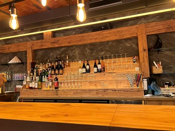 Hof Frien Bar Eine großzügige Bar aus Holz, gefüllt mit zahlreichen Flaschen und gläsernen Getränkebehältern.