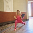 Heidi Lödige Heidi Lödige in pinkem Sportoutfit beim Ausfallschritt in einem lichtdurchfluteten Raum mit Yogamatte.