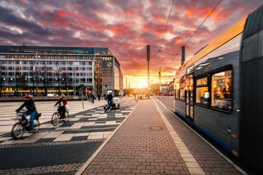 Augustusplatz Leipzig mit Straßenbahn und Radfahrern | Leipzig Convention Bureau Auf dem Augustusplatz in Leipzig fährt eine Straßenbahn und Radfahrer sind unterwegs – präsentiert vom Leipzig Convention Bureau