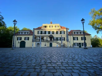 Schloss Eulenbroich Klassizistisches Herrenhaus in Rösrath mit gepflastertem Innenhof und blauen Fensterrläden.