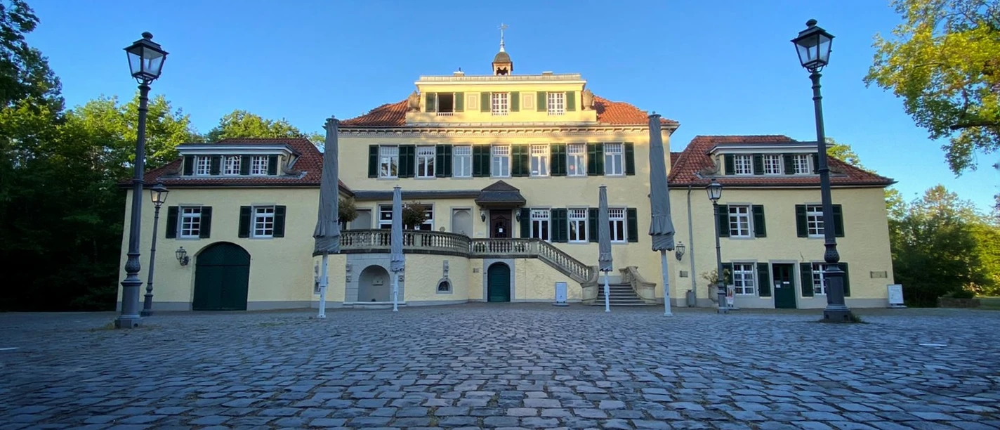 Schloss Eulenbroich Klassizistisches Herrenhaus in Rösrath mit gepflastertem Innenhof und blauen Fensterrläden.