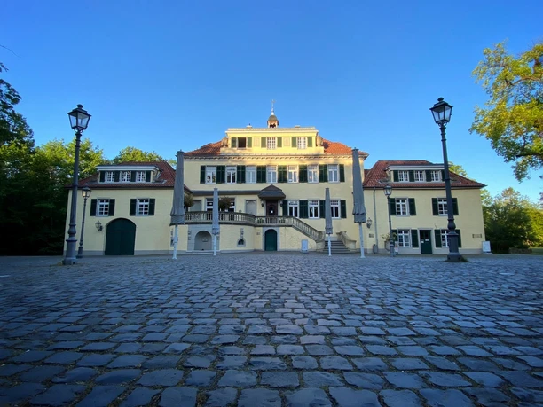 Schloss Eulenbroich Klassizistisches Herrenhaus in Rösrath mit gepflastertem Innenhof und blauen Fensterrläden.