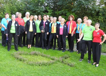 Bad-Driburg_Spirit-Voices_Gospelchor.jpg Mitglieder des Spirit Voices Gospelchors stehen lächelnd in bunter Freizeitkleidung auf einer Wiese.