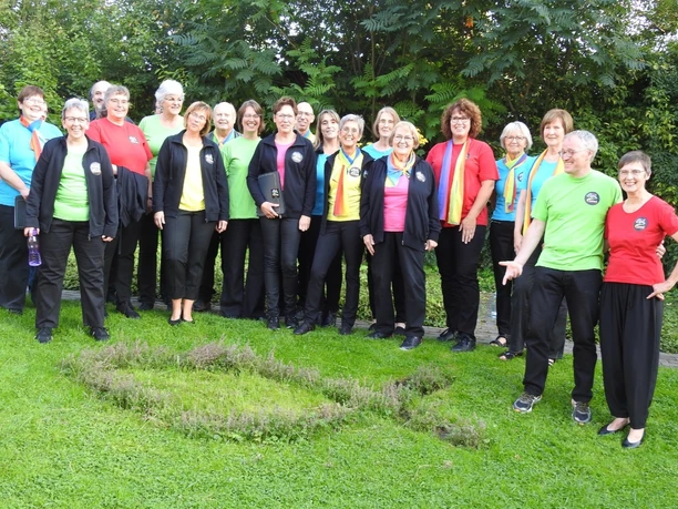 Bad-Driburg_Spirit-Voices_Gospelchor.jpg Mitglieder des Spirit Voices Gospelchors stehen lächelnd in bunter Freizeitkleidung auf einer Wiese.