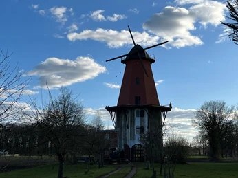Windmühle Diepenau-Lavelsloh Historische Windmühle mit roter Kappe und weißen Flügeln vor blauem Himmel mit leichten Wolken.