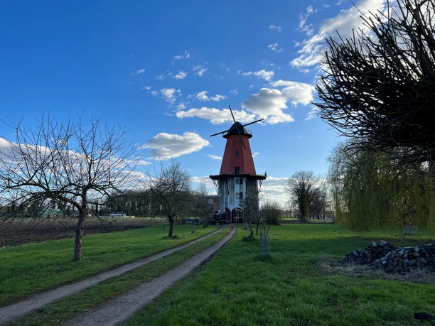 Windmühle Diepenau-Lavelsloh Windmühle in Diepenau-Lavelsloh mit rotem Turm und umliegendem Grün vor blauem Himmel mit Wolken.