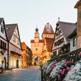 Historische Gasse mit Fachwerkhäusern, Blüten und einem Turm im Abendlicht