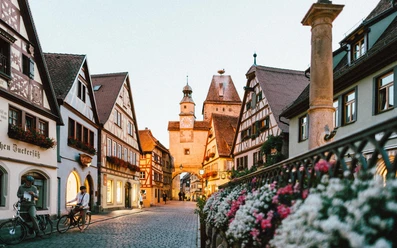 sample-5.jpg Historische Gasse mit Fachwerkhäusern, Blüten und einem Turm im Abendlicht