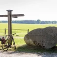 Thansen Fahrrad und Wegweiser am Stein mit Pferderelief vor weiten Feldern in Thansen.