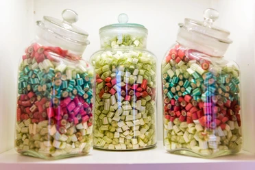 Dosen voller Bonbons Drei Glasbehälter mit bunten Bonbons in Rot, Grün und Blau auf einem Regal; die Atmosphäre wirkt nostalgisch und einladend.