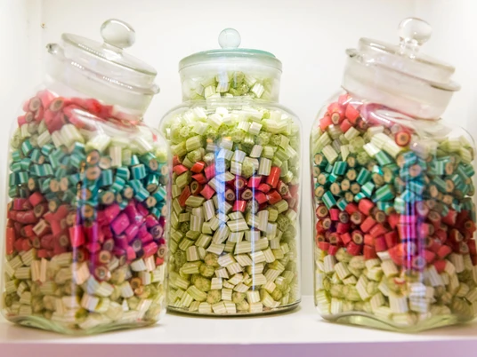 Dosen voller Bonbons Drei Glasbehälter mit bunten Bonbons in Rot, Grün und Blau auf einem Regal; die Atmosphäre wirkt nostalgisch und einladend.